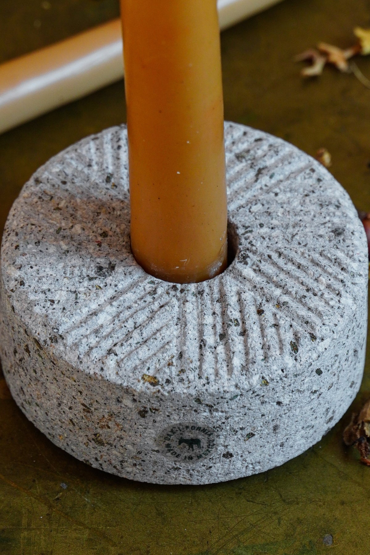 Oax-i-fornia Molino stone candleholder on a table, featuring a rustic, handcrafted design with a wide base and pillar holder