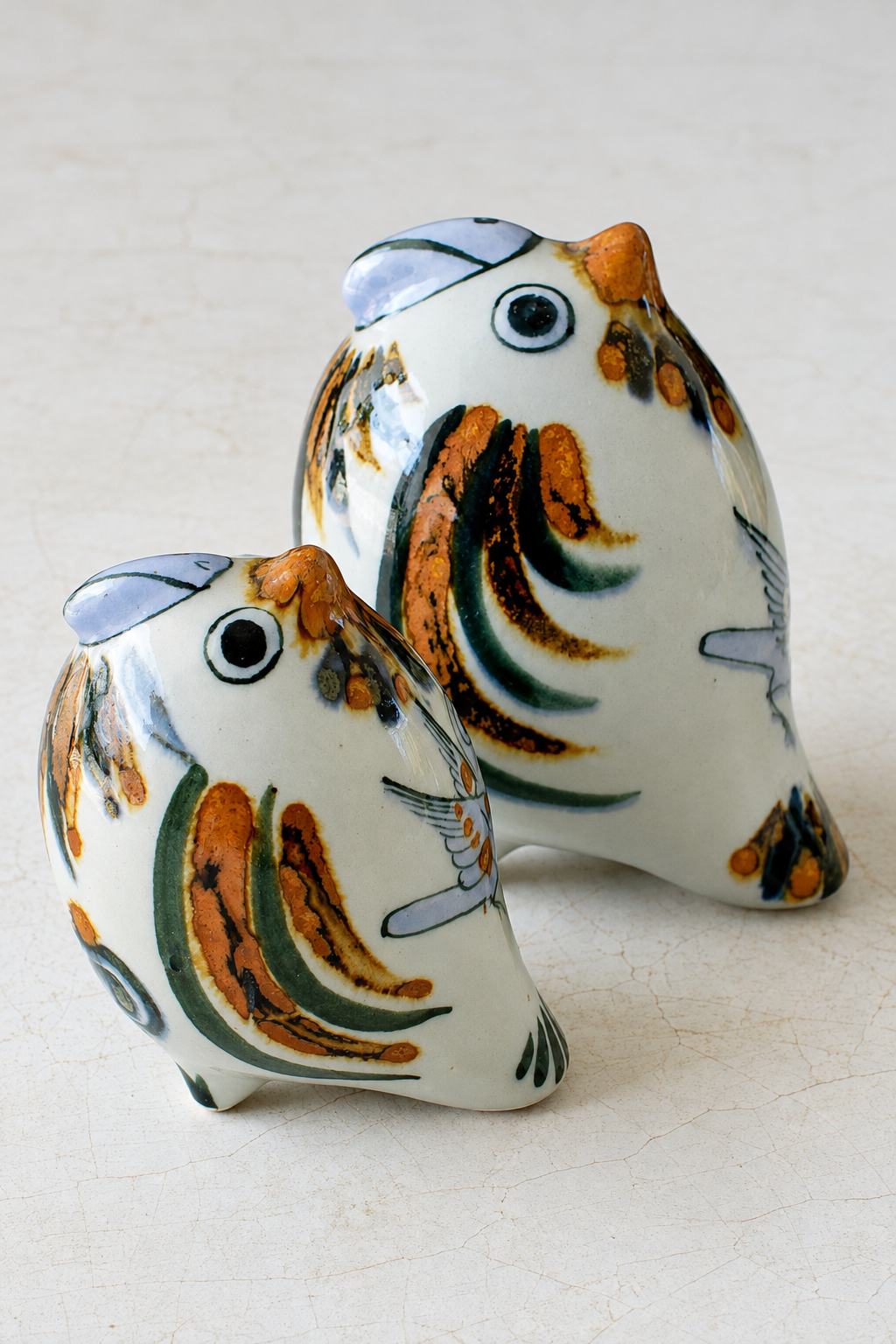 Hand-painted ceramic parrot home decor by Embajada Craft, featuring colorful bird designs on crackled stone background.